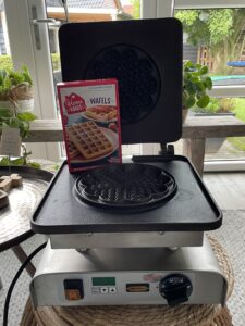 Een wafelijzer met een pak wafelmeel